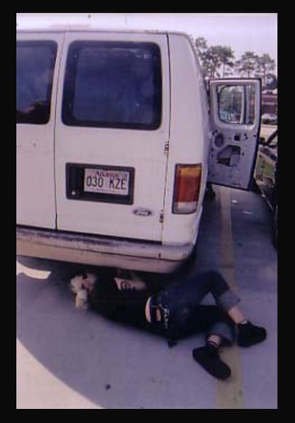 a photo of someone crawling under a van to fix it