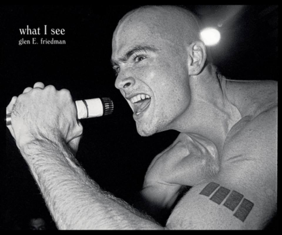 a black and white photograph of a bald white man screaming into a microphone