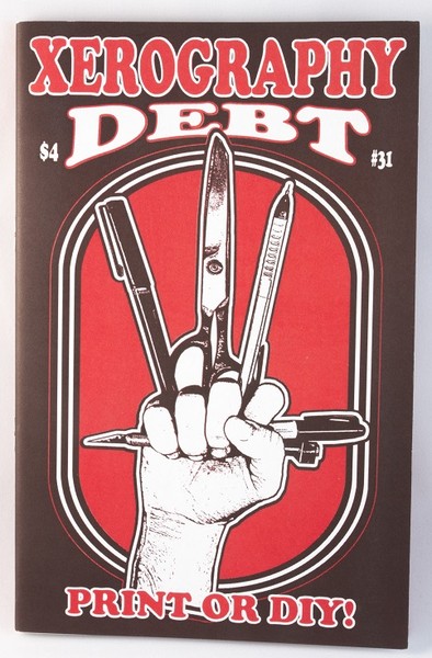 A red and black zine with an illustration of a clenched fist with a pencil, scissors, pens, and markers clutched between the fingers