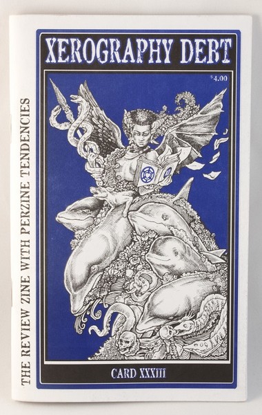 A blue zine with an illustration of a demonic/angelic looking women (with horns and wings) riding on a pile of objects and subjects including a skull and two dolphins
