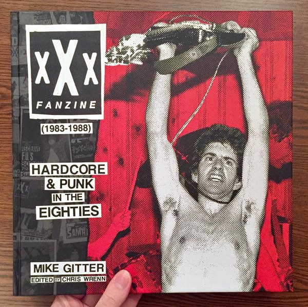 Cover of xXx Fanzine (1983-1988) which features a topless man holding a guitar over his head as if in victory